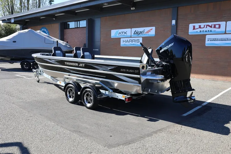 Slide: The Image of 2026 Thunder Jet 229 Rush OT boat with Mercury engine on a trailer, parked outdoors. - 21
