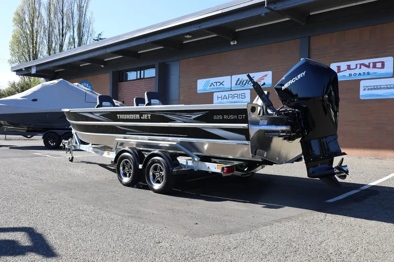 Slide: The Image of 2026 Thunder Jet 229 Rush OT boat with Mercury engine on trailer, parked outdoors. - 22