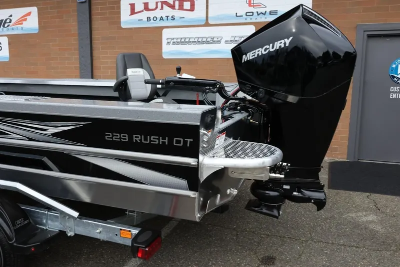 Slide: The Image of 2026 Thunder Jet 229 Rush OT boat with Mercury engine, parked outdoors. - 4