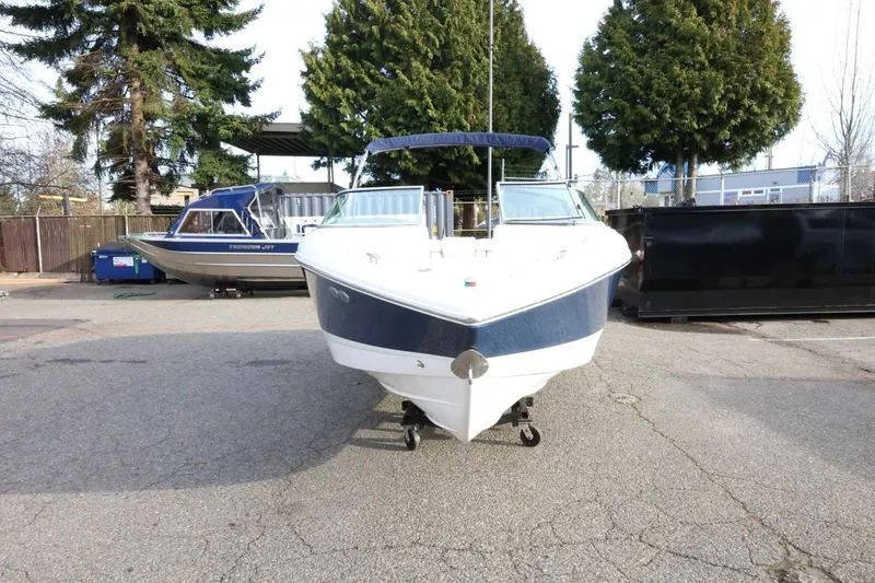 Slide: The Image of 2005 Cobalt 200 boat parked outdoors, surrounded by trees and other boats. - 4