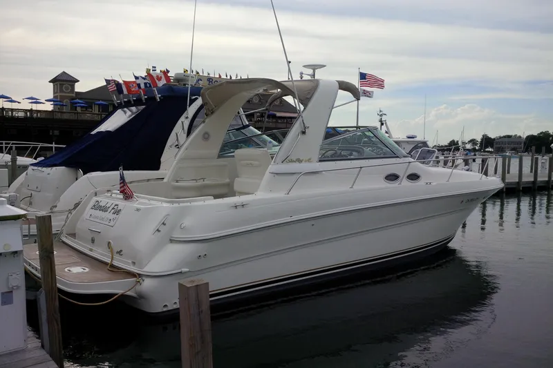 Slide: The Image of 2000 Sea Ray 310 Sundancer docked at marina with flags and clear sky. - 3