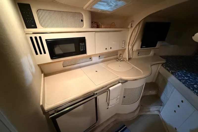 Slide: The Image of 2000 Sea Ray Sundancer 310 interior kitchen with microwave, sink, and storage cabinets. - 38