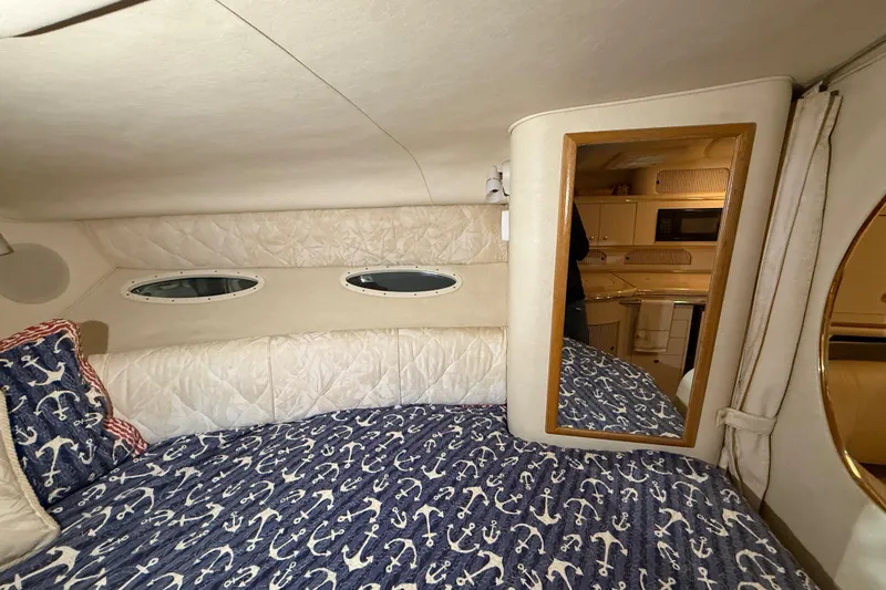 Slide: The Image of Interior of 2000 Sea Ray Sundancer 310 with nautical-themed bedding and porthole windows. - 42