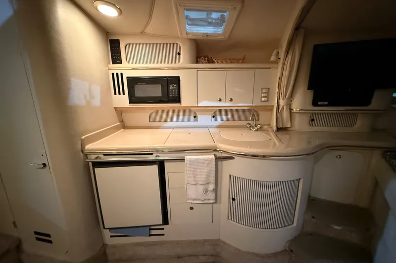 Slide: The Image of 2000 Sea Ray Sundancer 310 yacht interior kitchen with microwave, sink, and cabinets. - 44
