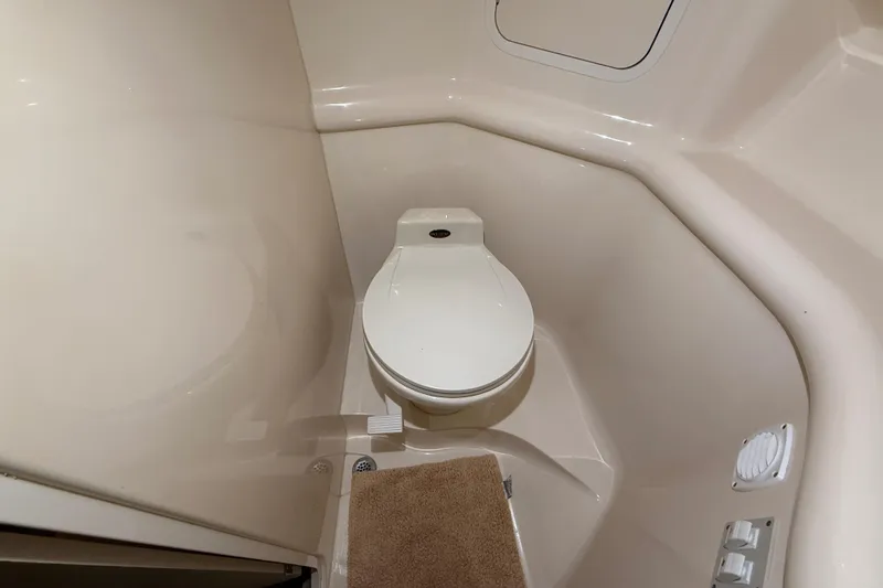 Slide: The Image of 2000 Sea Ray Sundancer 310 boat bathroom with compact toilet and beige interior. - 57