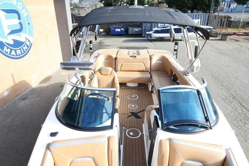 Slide: The Image of 2020 MasterCraft XStar boat with tan interior and black canopy, docked at a marina. - 21