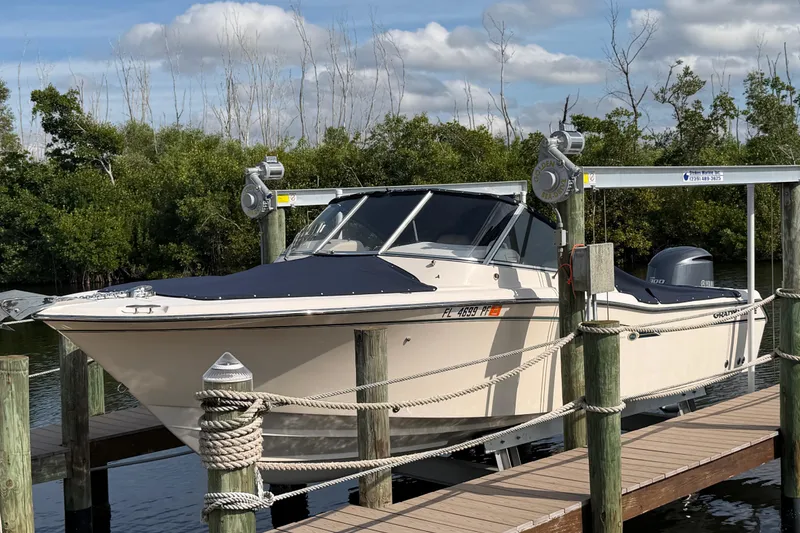 The Image of 2011 Grady-White Freedom 255 boat docked on a lift, surrounded by lush greenery. - 0