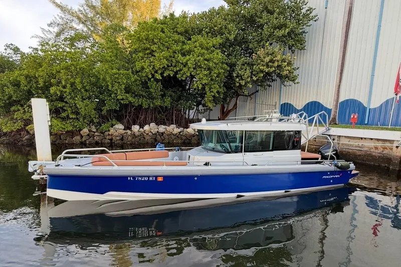 The Image of 2019 Axopar 28 Cabin boat docked by a lush, green shoreline. - 0