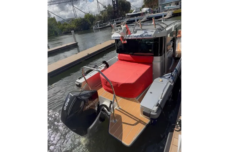 Slide: The Image of 2019 Axopar 28 Cabin boat docked, featuring a red cover and Mercury outboard motor. - 11