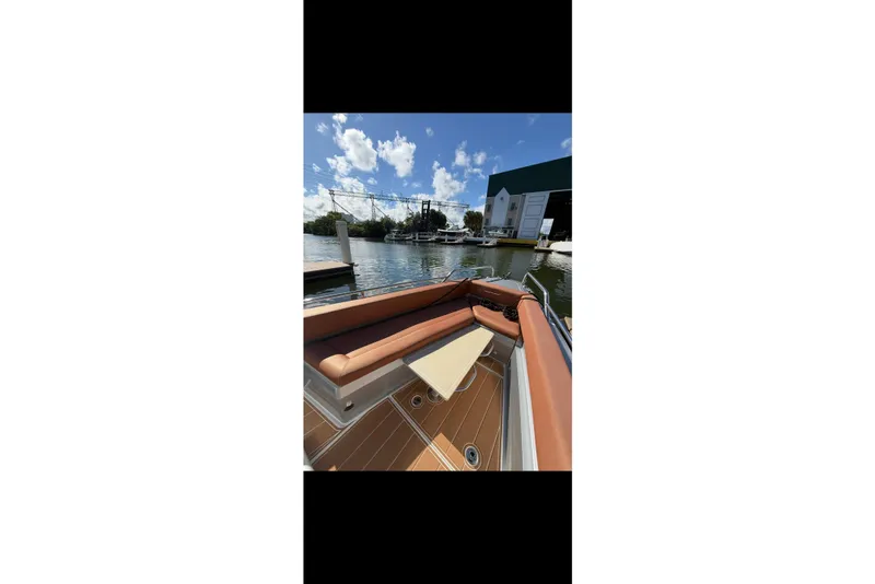 Slide: The Image of 2019 Axopar 28 Cabin boat interior with brown seating, docked by a marina. - 13