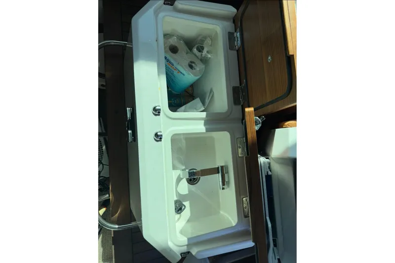 Slide: The Image of 2019 Axopar 28 Cabin sink with storage, featuring paper towels and cleaning supplies. - 21