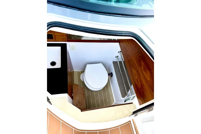 Slide: The Image of 2019 Axopar 28 Cabin boat interior with compact bathroom and wooden accents. - 24