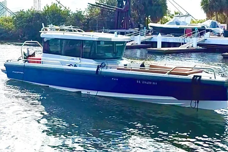 Slide: The Image of 2019 Axopar 28 Cabin boat docked in a marina, surrounded by water and greenery. - 5