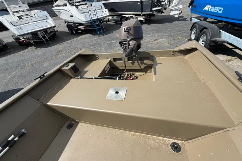 Slide: The Image of 2026 G3 Gator Tough Package Jon 15 FL boat, tan interior, outboard motor, parked among other boats. - 7