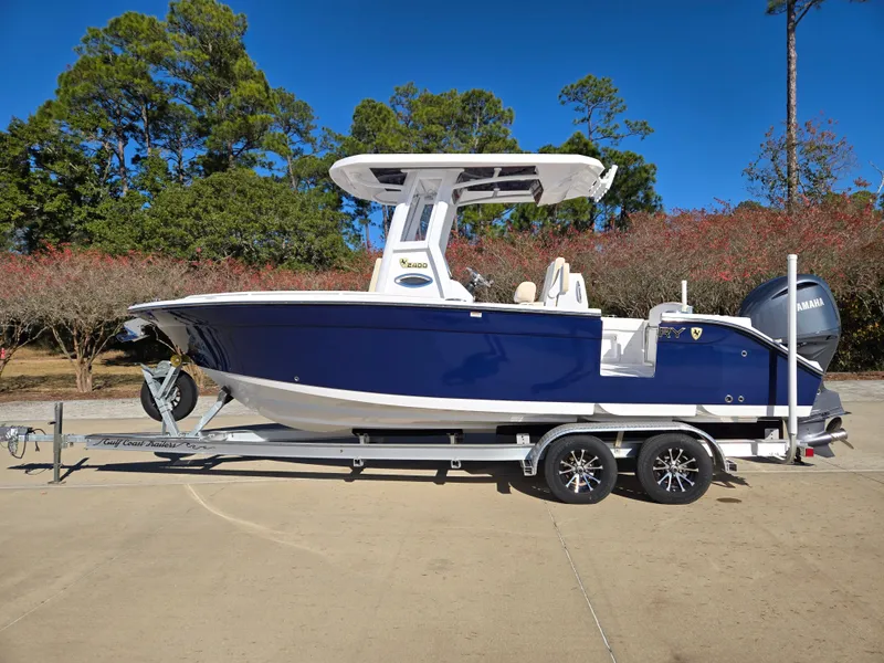 The Image of 2024 Century 2400CC boat on trailer, blue design, parked outdoors. - 0