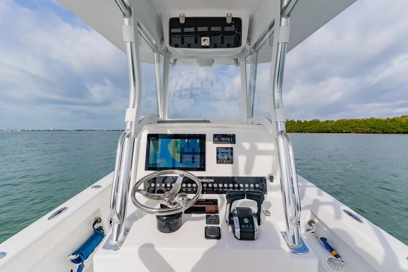 Slide: The Image of 2024 Orion 29CC boat dashboard with steering wheel and navigation equipment on open water. - 36