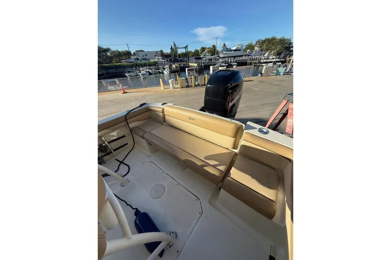 Slide: The Image of 2018 Scout 225 XSF boat interior with seating and outboard motor at dock. - 11