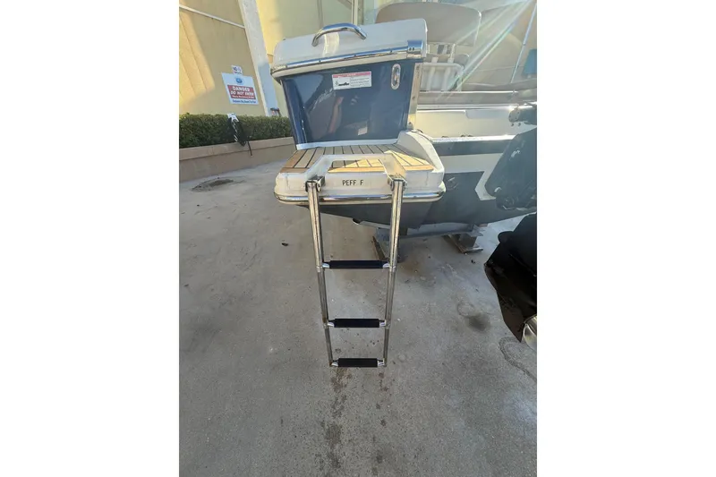 Slide: The Image of 2018 Scout 225 XSF boat with a foldable swim ladder on a concrete surface. - 25