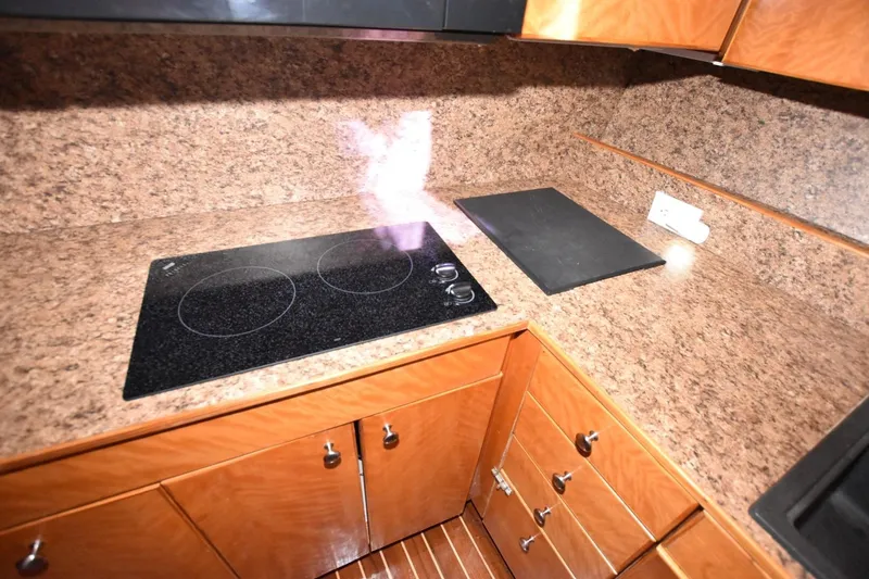 Slide: The Image of 1990 Ocean Yachts 48 Super Sport kitchen with electric stovetop and wooden cabinetry. - 16