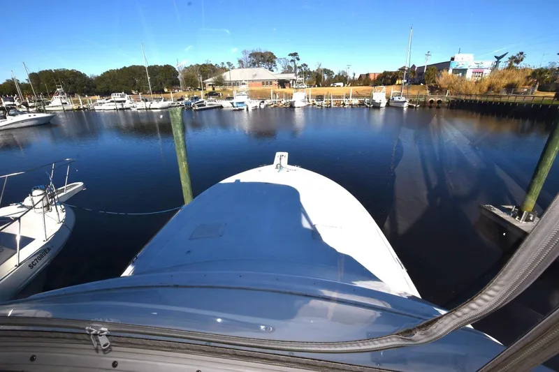 Slide: The Image of 1990 Ocean Yachts 48 Super Sport docked in a serene marina under clear blue skies. - 2