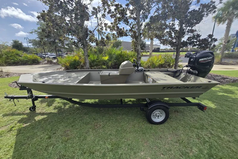 The Image of 2026 Tracker Grizzly 1648 SC boat on trailer, parked on grass with trees in background. - 0