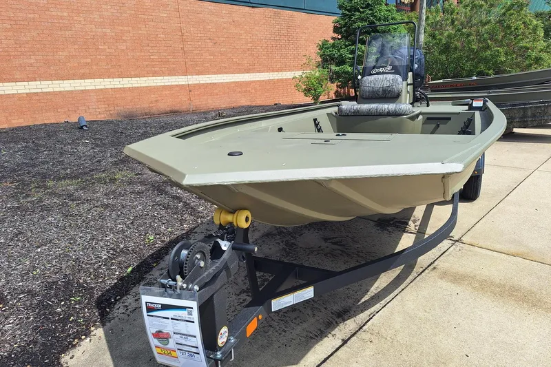 Slide: The Image of 2026 Tracker Grizzly 1860 CC boat on trailer, displayed outdoors near a brick wall. - 2