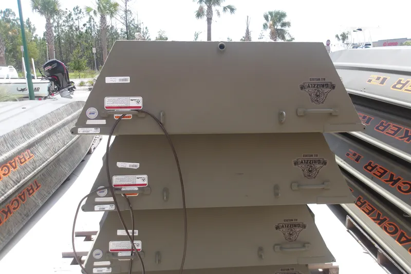 Slide: The Image of Stacked 2026 Tracker Grizzly 14 Jon boats displayed outdoors. - 2