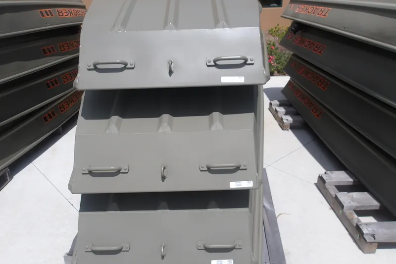 Slide: The Image of 2026 Tracker Grizzly 12 Jon boat hulls stacked on pallets outdoors. - 4