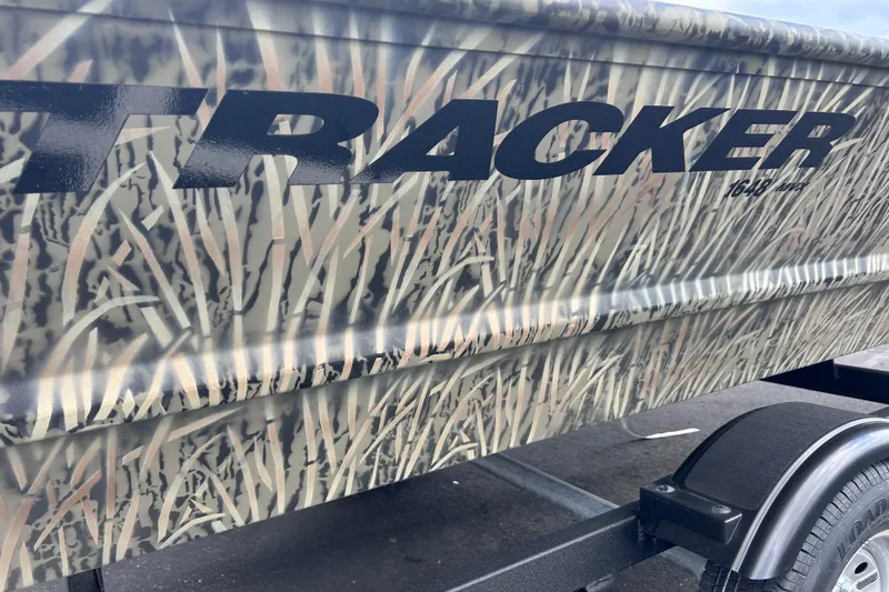 Slide: The Image of 2026 Tracker Grizzly 1648 Utility boat with camouflage design on trailer. - 5