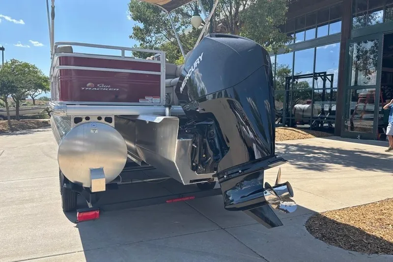 Slide: The Image of 2026 Sun Tracker Party Barge 22 RF XP3 with Mercury outboard motor, parked outdoors. - 98