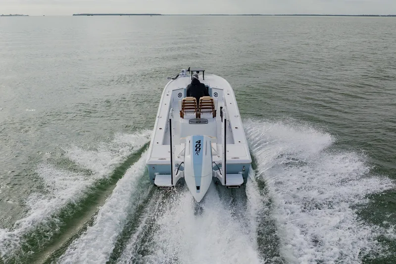 Slide: The Image of Broadwater 25 Bay Cat 2026 cruising on open water, rear view, creating waves. - 13