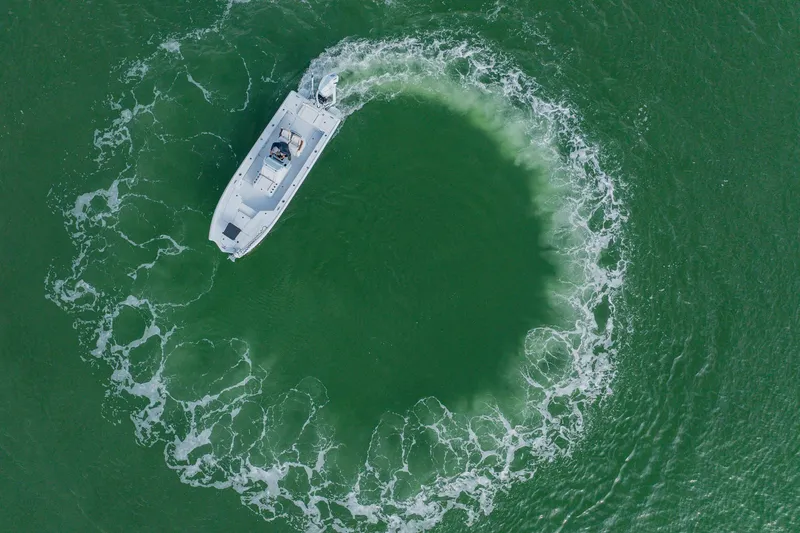 Slide: The Image of Aerial view of 2026 Broadwater 25 Bay Cat creating circular wake in green water. - 14