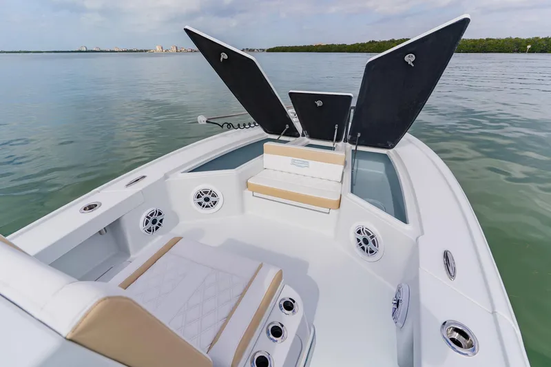 Slide: The Image of 2026 Broadwater 25 Bay Cat boat interior with open storage compartments on calm water. - 15