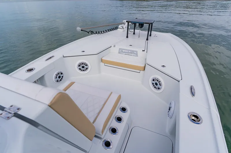 Slide: The Image of 2026 Broadwater 25 Bay Cat boat interior with seating and speakers on calm water. - 16