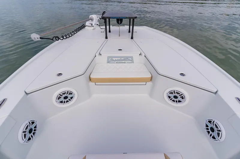 Slide: The Image of 2026 Broadwater 25 Bay Cat boat interior with seating and speakers on calm water. - 18
