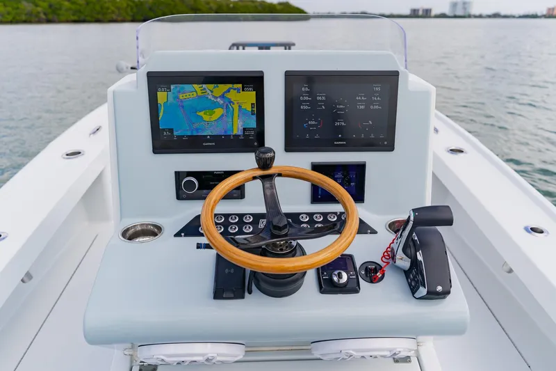 Slide: The Image of Control console of 2026 Broadwater 25 Bay Cat boat with dual screens and wooden steering wheel. - 27