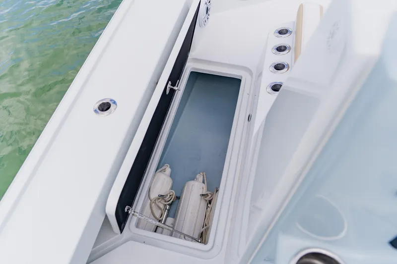 Slide: The Image of 2026 Broadwater 25 Bay Cat boat storage compartment with fenders, docked on water. - 30