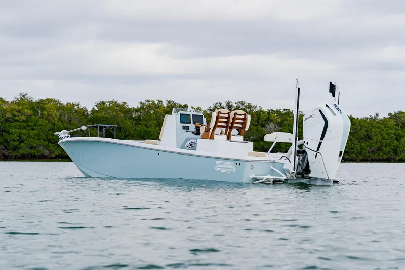 Slide: The Image of 2026 Broadwater 25 Bay Cat boat on calm water near lush greenery. - 4