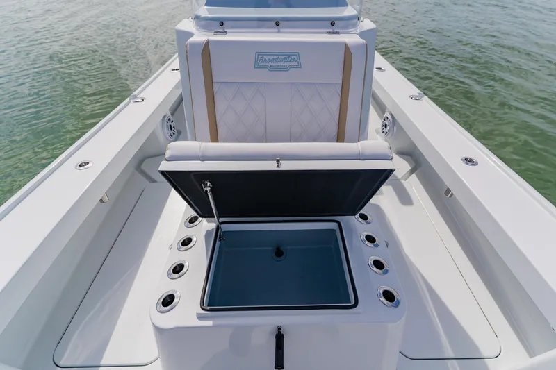 Slide: The Image of 2026 Broadwater 25 Bay Cat boat interior with open storage compartment on water. - 45