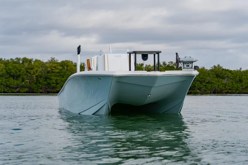 Slide: The Image of 2026 Broadwater 25 Bay Cat boat on calm water, front view. - 6