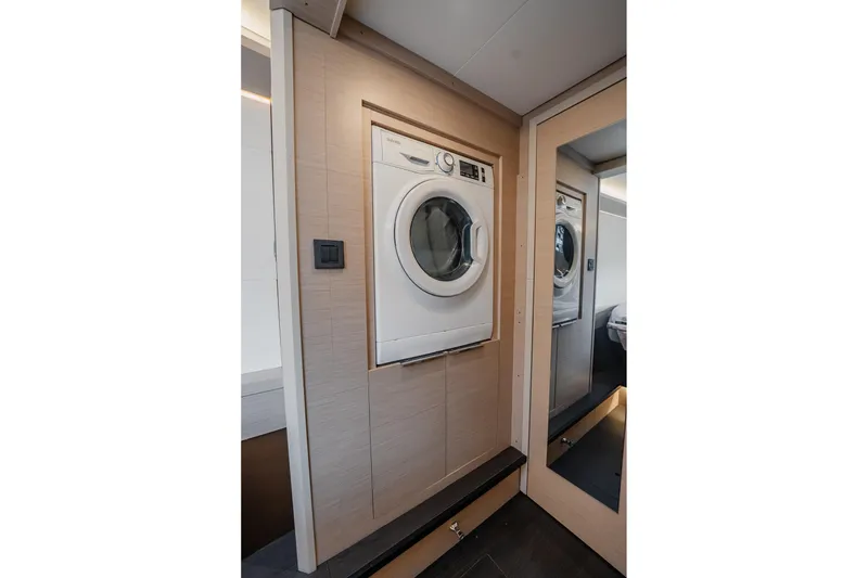 Slide: The Image of Laundry area inside 2022 Lagoon 46 yacht, featuring a modern washing machine. - 104