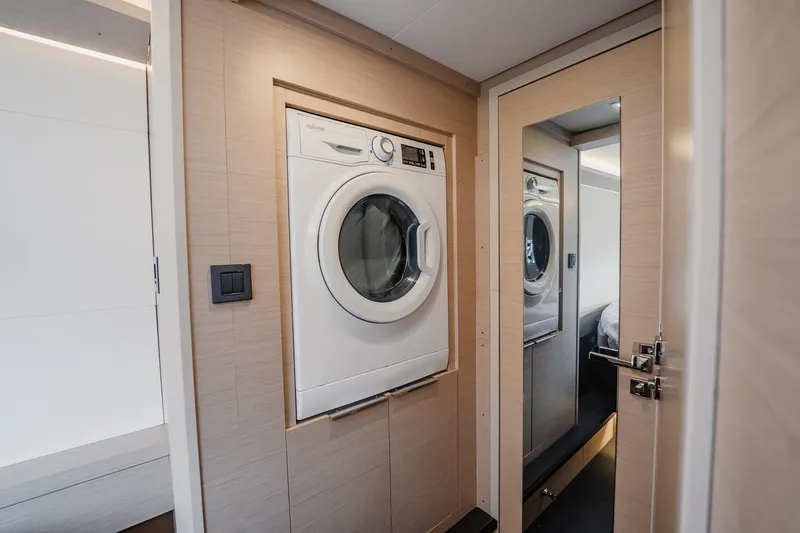 Slide: The Image of Laundry area inside 2022 Lagoon 46 yacht, featuring a modern washing machine. - 105