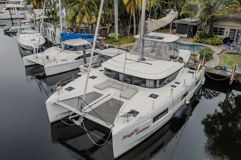Slide: The Image of 2022 Lagoon 46 catamaran docked in a marina, surrounded by palm trees. - 124