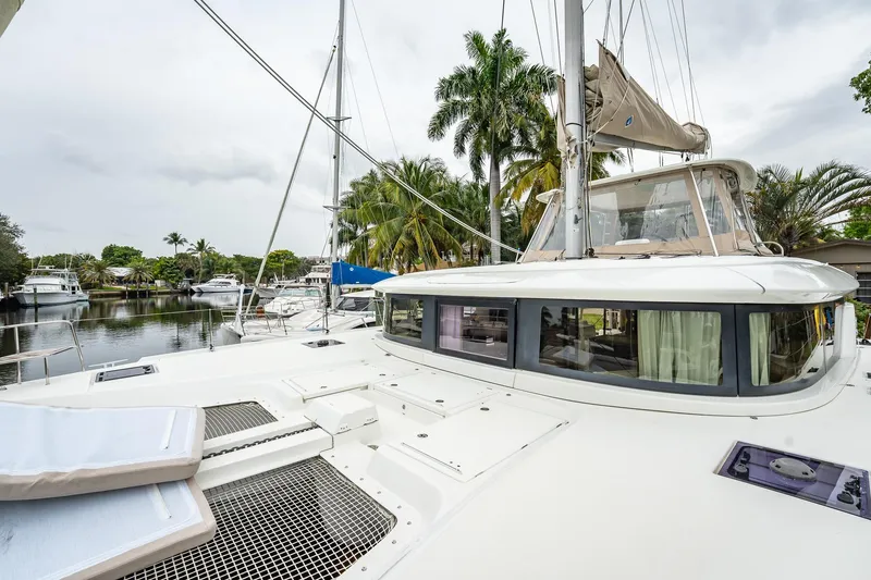 Slide: The Image of 2022 Lagoon 46 catamaran docked near palm trees, showcasing sleek design and spacious deck. - 141