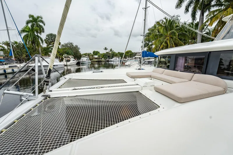 Slide: The Image of 2022 Lagoon 46 catamaran with spacious deck and netting, docked near palm trees. - 153