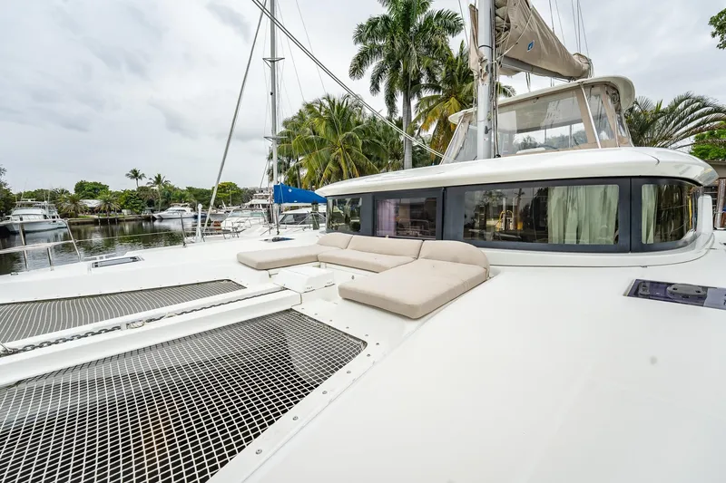 Slide: The Image of 2022 Lagoon 46 catamaran with spacious deck and lounging area, docked near palm trees. - 157