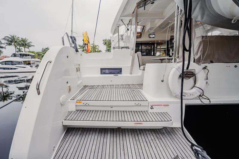 Slide: The Image of 2022 Lagoon 46 yacht stern view with steps and lifebuoy in marina setting. - 32