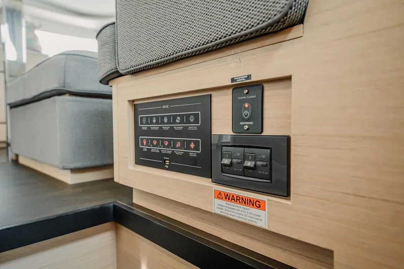 Slide: The Image of Control panel on 2022 Lagoon 46 yacht interior, featuring switches and warning label. - 49