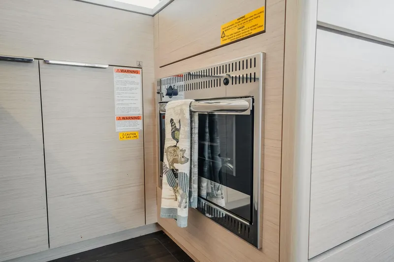 Slide: The Image of Modern kitchen area in 2022 Lagoon 46 yacht with oven and safety warnings. - 97