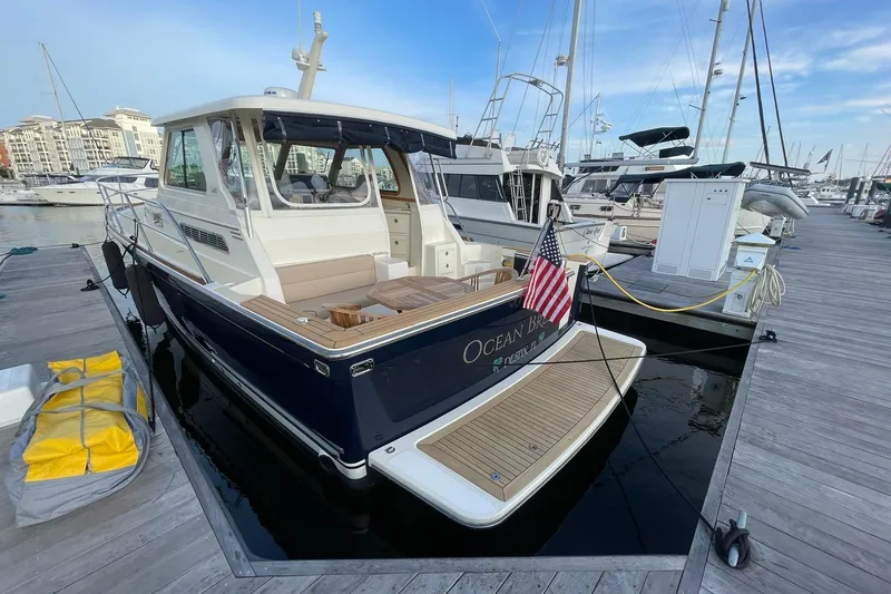 Slide: The Image of 2008 Sabre 38 Salon Express yacht docked at marina, featuring American flag and wooden deck. - 3